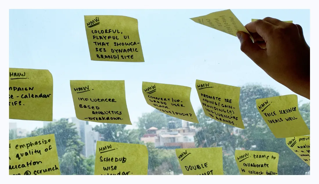 Hand placing How Might We sticky notes on a window