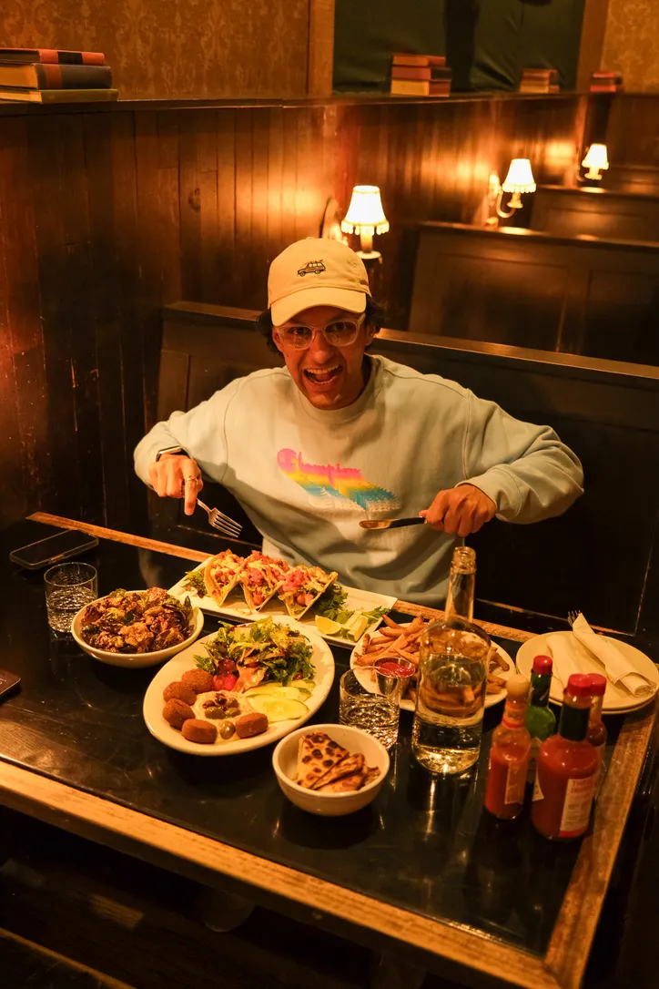 Swapnil smiling at a restaurant table full of dishes